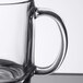 An Arcoroc tempered glass mug with a handle on a table.