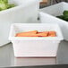 A white Rubbermaid food storage container with carrots in it.