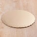 A gold laminated cake circle on a wood surface.