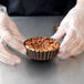 A person in gloves holding a Gobel fluted deep tart pan filled with food.