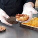 A person in gloves placing pastry in a Gobel fluted deep tart pan.