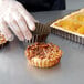 A hand in a plastic glove placing pastry into a Gobel fluted tart pan.