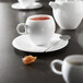 A close-up of a white Chef & Sommelier bone china coffee cup with tea on a table.