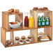 A Cal-Mil bamboo display riser with food and drinks on wooden shelves.