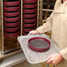 A man using a Cambro Camduction Charger to heat a round container.