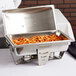 A Vollrath Maximillian stainless steel chafer on a hotel buffet table full of food.