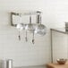 A kitchen with pots and pans hanging on a Regency stainless steel wall mounted double line pot rack.