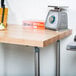 An Advance Tabco wood top work table with a scale and a knife on it.