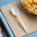 A white plastic spork next to a bowl of macaroni and cheese.