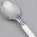 A WNA Comet Reflections Duet stainless steel look teaspoon with a white handle.