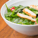An Arcoroc Vintage bowl filled with spinach and chicken salad on a table.