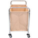 A beige metal Luxor commercial laundry hamper on wheels and with a handle.