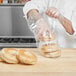 A person in a chef's uniform putting bagels in a plastic bread bag.