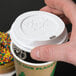 A hand placing a white Eco-Products lid on a coffee cup.