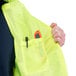 A person wearing a Cordova lime high visibility safety vest with a pocket and a pen in it.