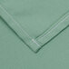 A seafoam green rectangular fabric with white stitching.