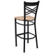 A Lancaster Table & Seating black cross back bar stool with a wooden seat.