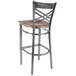 A Lancaster Table & Seating metal cross back bar stool with a wood seat.