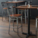 A Lancaster Table & Seating cross back bar stool with a wooden seat on a table in a restaurant.