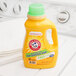A yellow bottle of Arm & Hammer 50 oz. liquid laundry detergent on a washing machine.