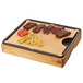 A Cal-Mil Madera carving station with meat and vegetables on a wooden cutting board.