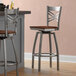 Two Lancaster Table & Seating swivel bar stools with wooden seats and metal legs at a counter.