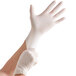 A person putting on a white disposable latex glove.