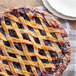 A pie with a lattice top and mixed berries on top.