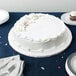 A white cake with frosting on a white Enjay round cake board.