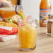 A hand pouring Nantucket Nectars Peach Orange Juice from a glass bottle into a glass.