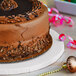 A chocolate cake on an Enjay white round cake board with chocolate shavings on top.