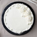 A white cake with white frosting on a black Enjay round cake board.