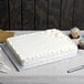 A white cake on an Enjay silver cake board on a table.