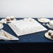 A white cake on a table with a silver square cake drum underneath.