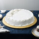 A white cake on a gold Enjay round cake drum on a table.