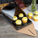 An Enjay black quad cupcake tulip box with cupcakes on a table.