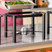 A black wrought iron pillar chafer stand designed to hold a half-size food pan for buffet or catering use.
