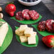 A plate of cheese and fruit on a table with American Metalcraft leaf cheese paper.