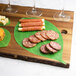 American Metalcraft Leaf Cheese Paper on a wooden surface with cheese, meat, and crackers.