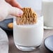 A hand holding a Keebler Oatmeal cookie over a glass of milk.