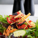 A salad with Fresh Gourmet tri-color tortilla strips, vegetables, and fruit on a table.