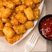 A plate of Ore-Ida Golden Tater Tots with ketchup and a fork.