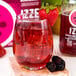 A glass of red Izze sparkling blackberry juice with ice cubes.