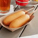 Two State Fair corn dogs in a paper tray on a table in a stadium concession stand.