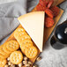 A wooden board with a wedge of BelGioioso Parmesan cheese and crackers.