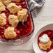 A bowl of strawberry cobbler with whipped cream on top.
