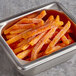 A metal container filled with McCain Harvest Splendor sweet potato fries on a counter.