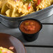 A bowl of nachos with a bowl of Rosarita medium green chile salsa on a table.
