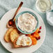 A bowl of Montena Ricotta cheese with a spoon next to a bowl of food.