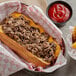 A sandwich with Original Philly Cheesesteak Co. beef, cheese, and ketchup in a basket.